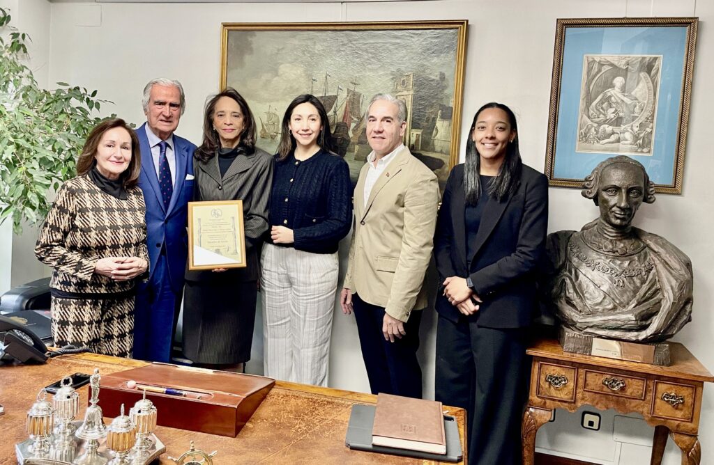 Grupo de personas en oficina con placa de reconocimiento.