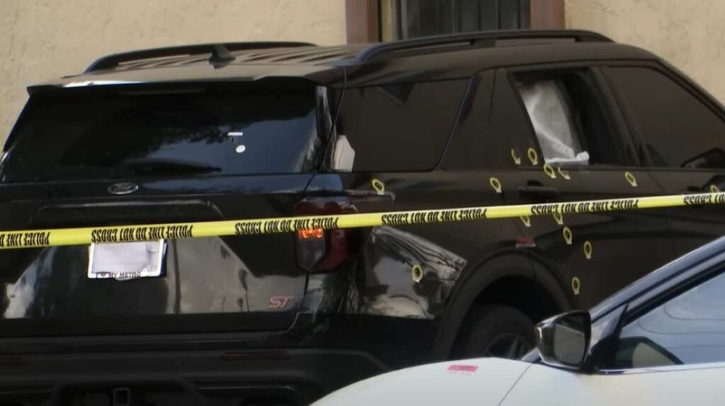 Cinta policial rodea coche con impactos de bala.