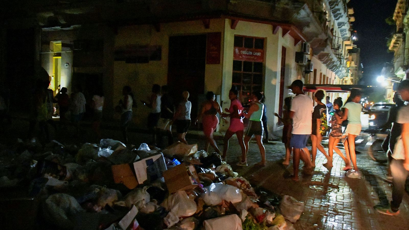 Personas caminaron por calle con basura y sin luz.