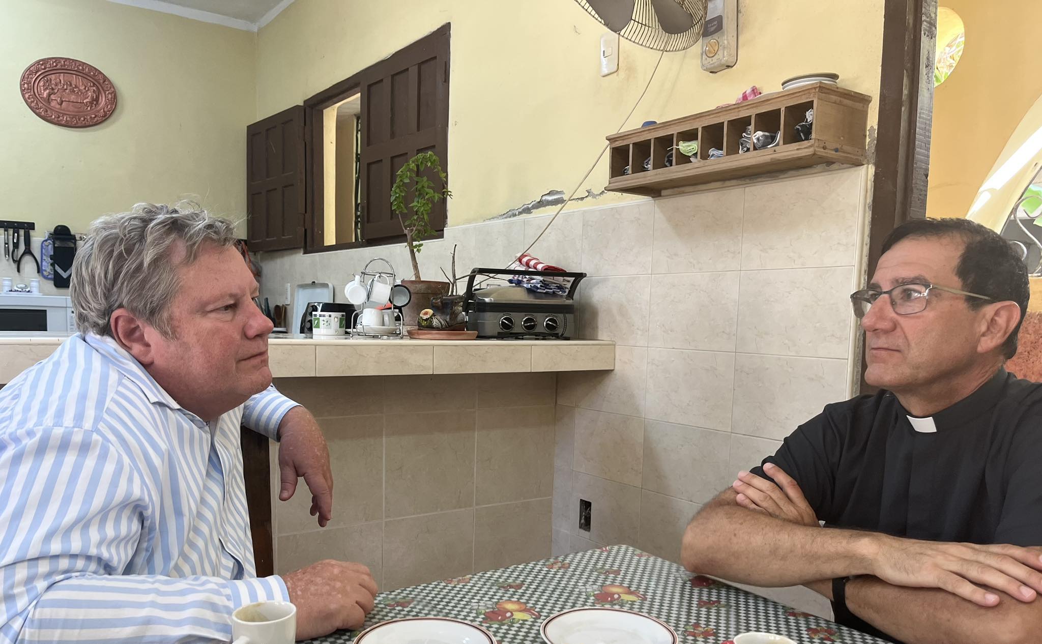 Dos hombres conversando en una cocina.