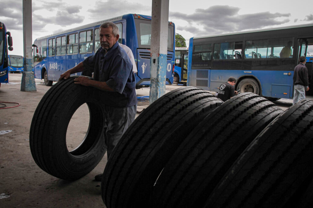 Hombre cambiando neumáticos de autobuses en taller