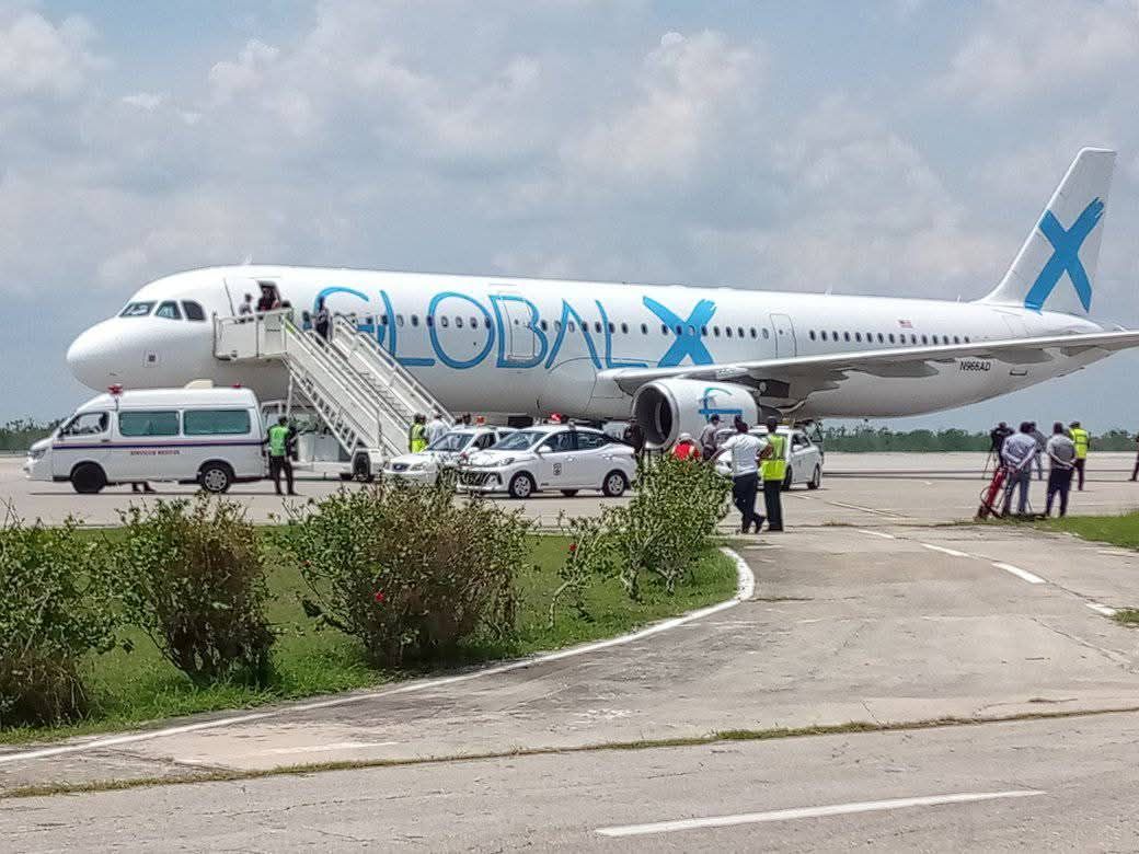 Avión en pista con escaleras y vehículos.