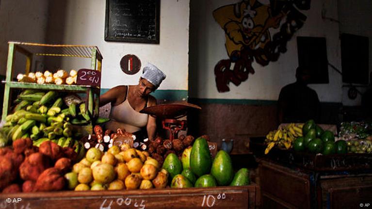 Vendedora organizando frutas en mercado local.