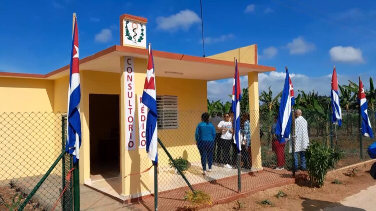 Consultorio médico con banderas, personas afuera.