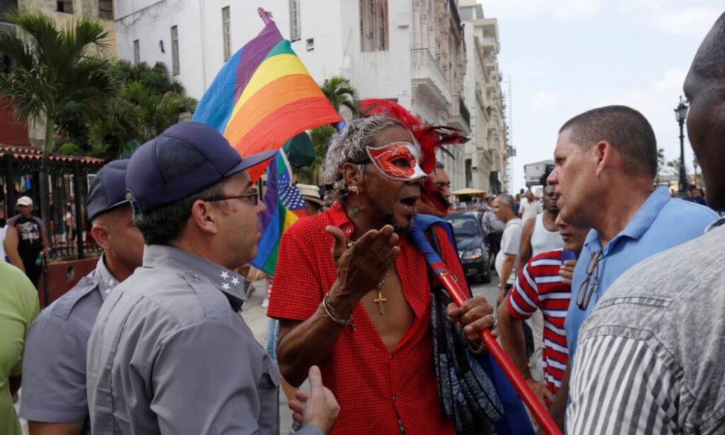 Discusión con bandera arcoíris en marcha callejera.