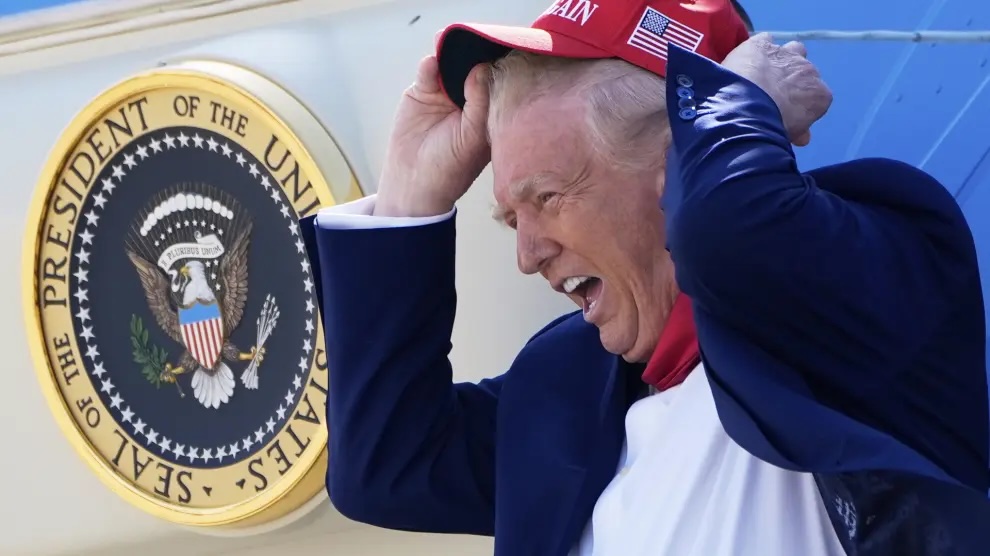 Hombre con gorra roja frente a sello presidencial.