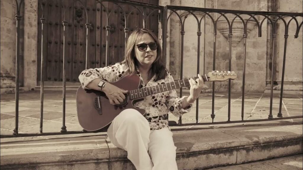 Mujer tocando guitarra en exterior histórico