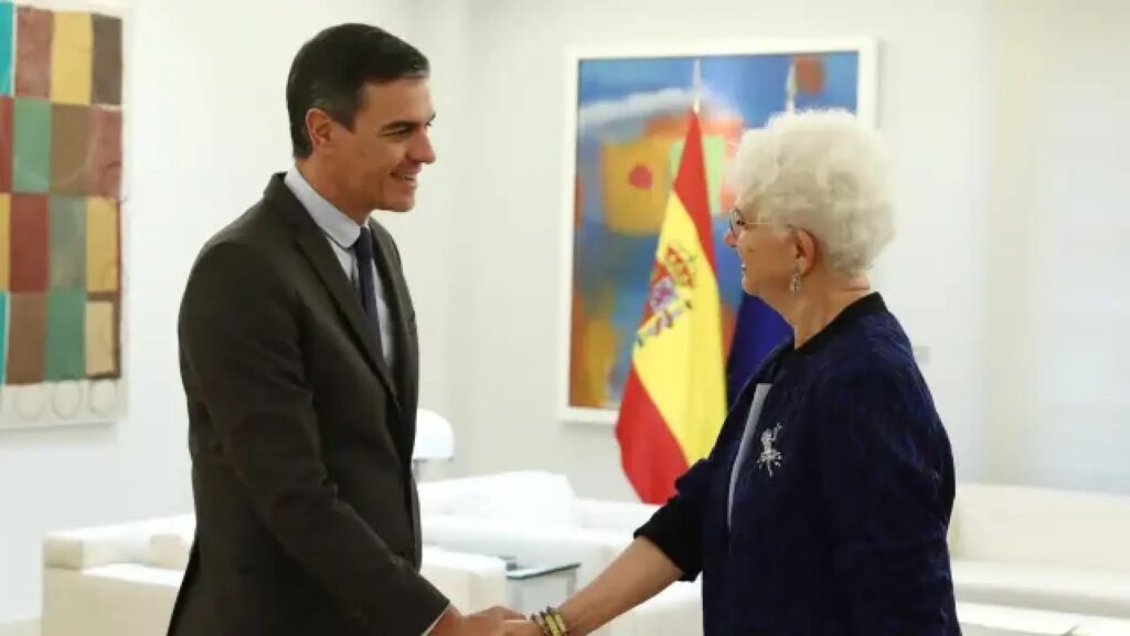 Persona en traje y mujer mayor dan la mano