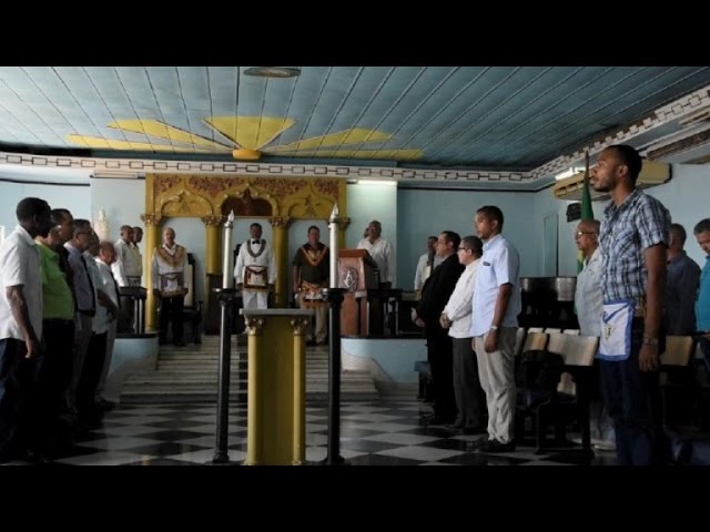Hombres reunidos en salón con decoración ceremonial.