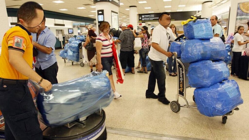 Personas en aeropuerto con equipaje envuelto.