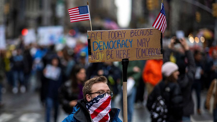 Manifestante con pancarta y banderas en protesta callejera.