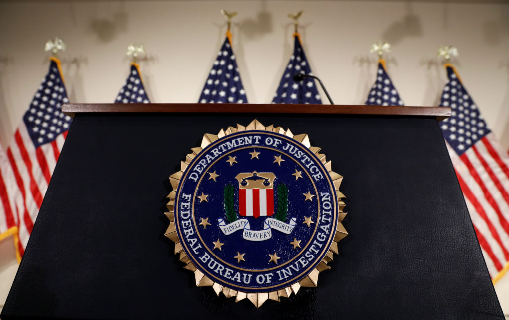 Podio del FBI con banderas estadounidenses detrás.
