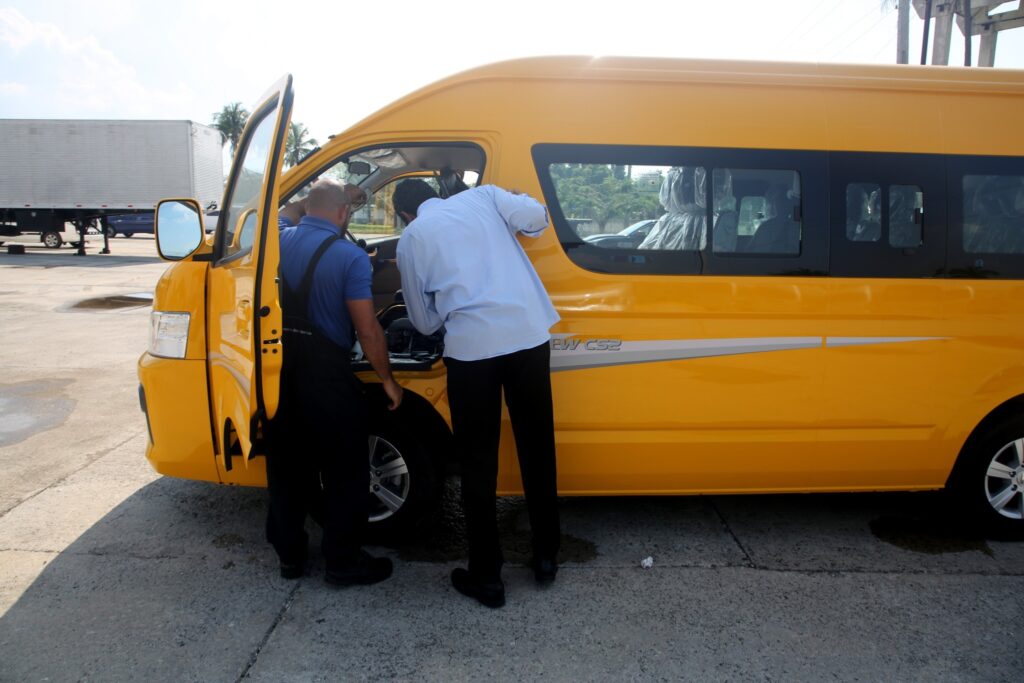 Mecánicos revisando motor de furgoneta amarilla en estación