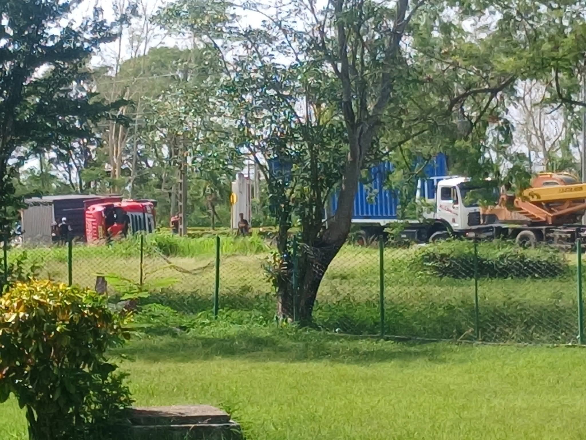 Camión volcado sobre césped cerca de árboles