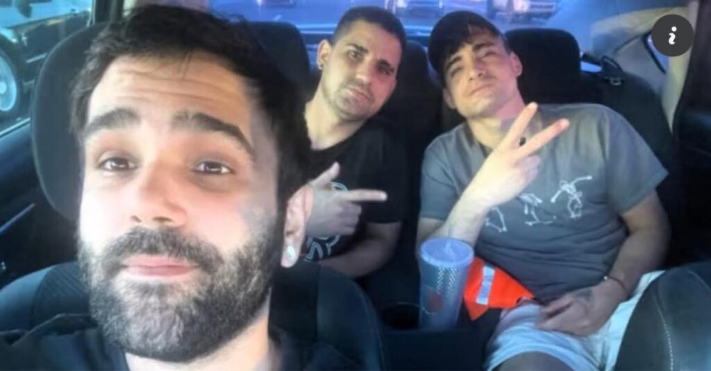 Tres personas en un coche, una hace gesto V.