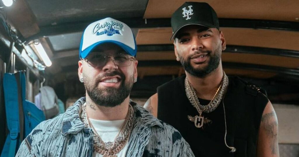 Dos hombres con gorras y cadenas sonriendo.