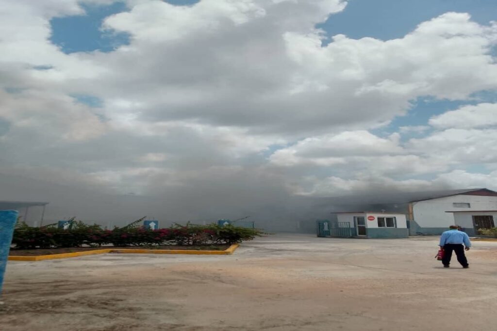 Humo denso cerca de edificio industrial con nubes.