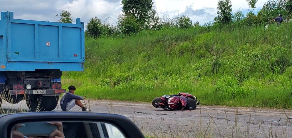 Moto caída en carretera junto a camión