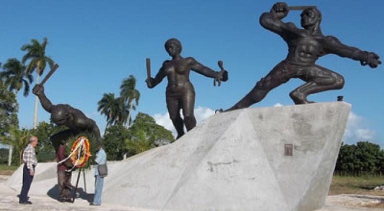Monumento histórico con esculturas y personas observando.