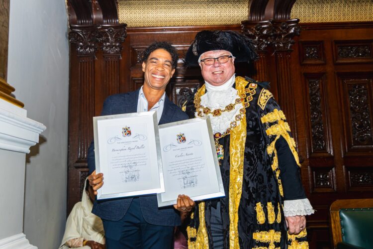 Dos personas con diplomas sonrientes y vestimenta ceremonial