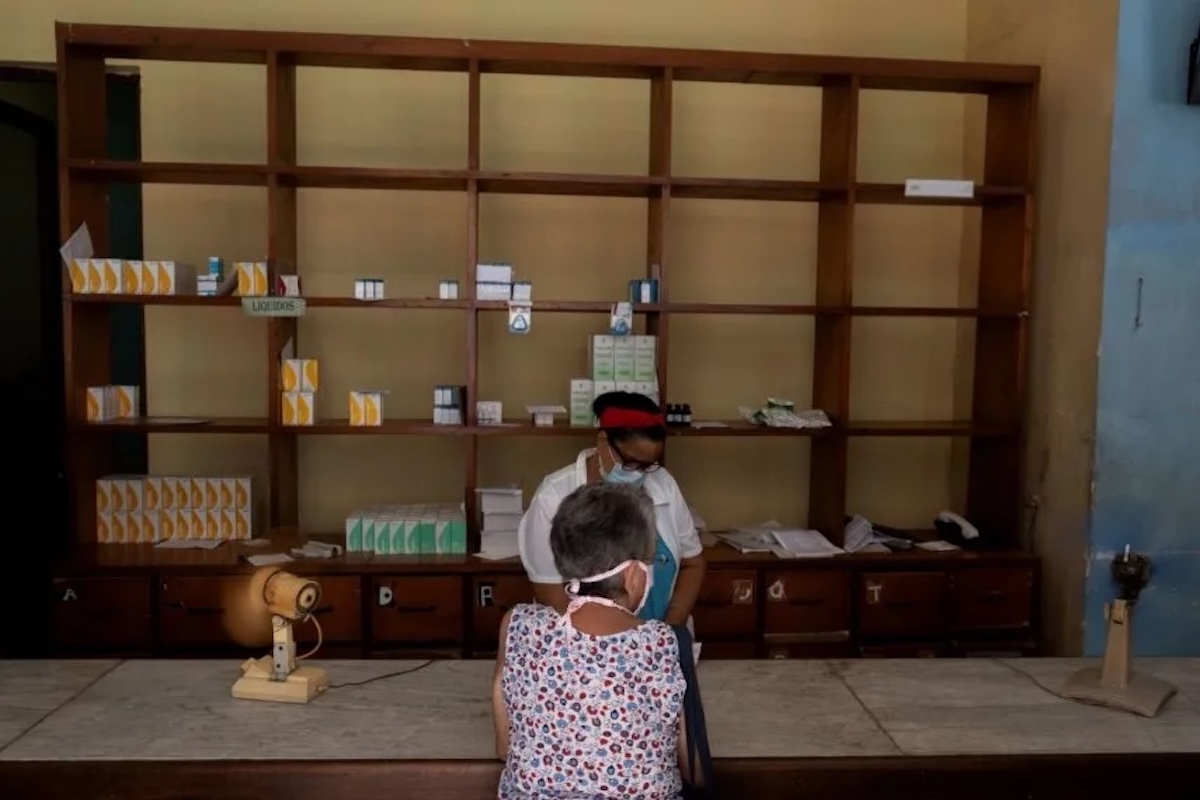 Persona en farmacia con estantes vacíos al fondo.