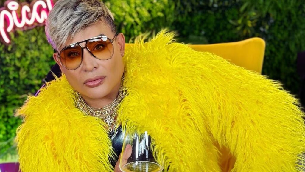 Persona con abrigo amarillo sosteniendo copa de vino.