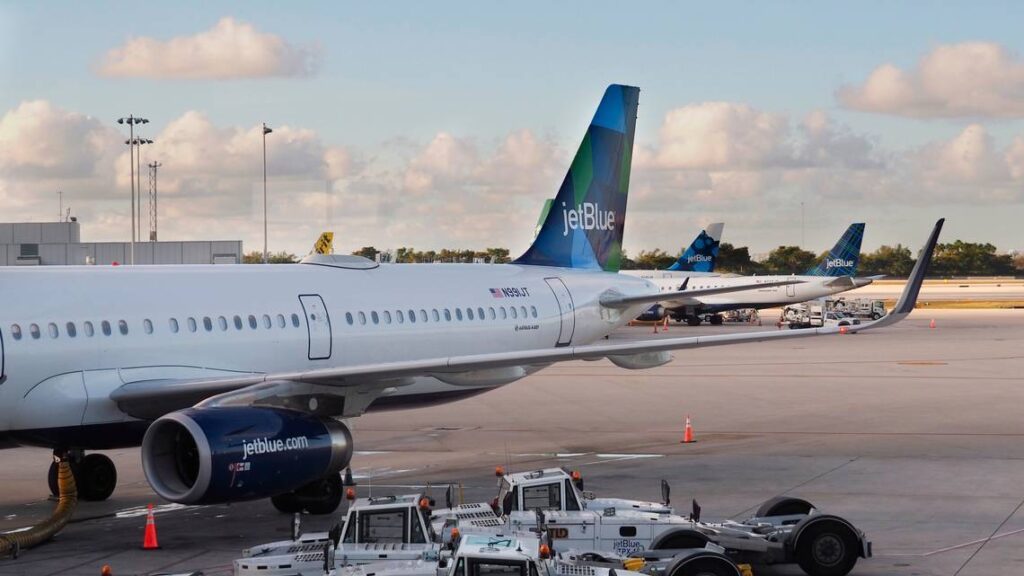 Avión en pista, aeropuerto al fondo.