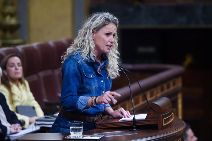 Mujer hablando en un podio en parlamento.