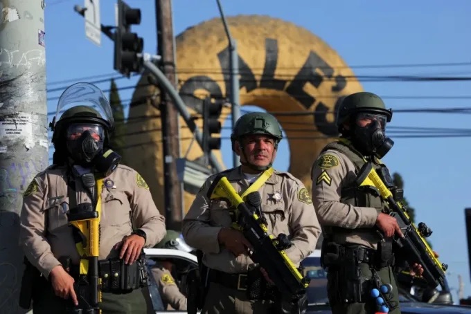 Policía en equipo táctico frente a gran donut.