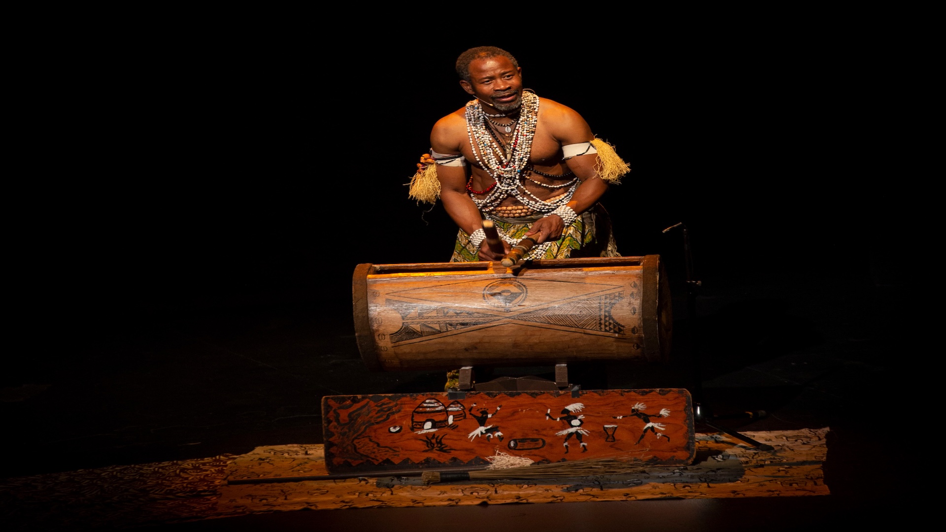 Hombre tocando tambor tradicional africano en escena