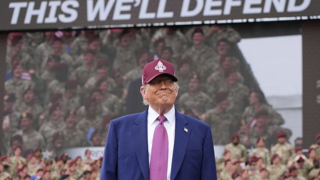 Persona con gorra frente a soldados y cartel.