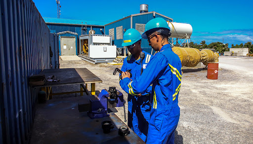 Trabajadores industriales con cascos revisando equipo.