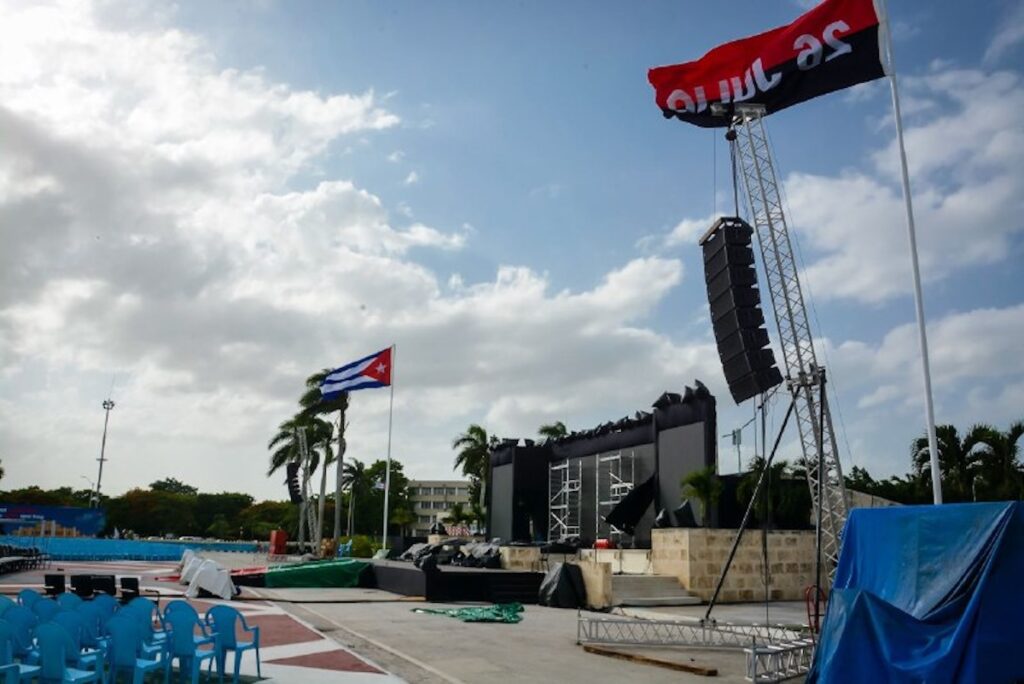 Escenario al aire libre con bandera cubana ondeando.
