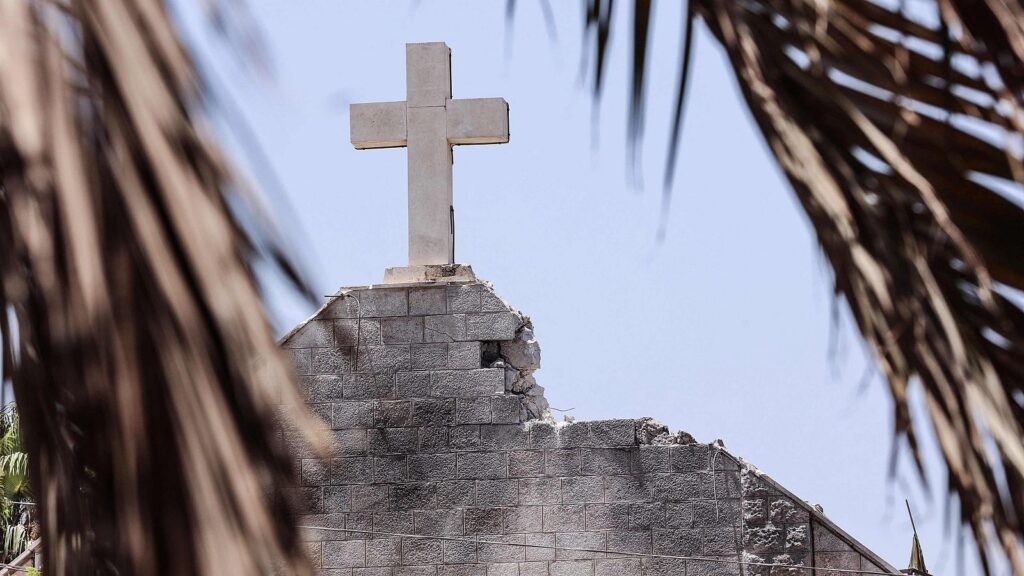 Iglesia con cruz en ruinas entre palmeras