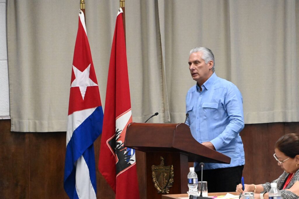 Persona hablando en un podio con banderas cubanas.