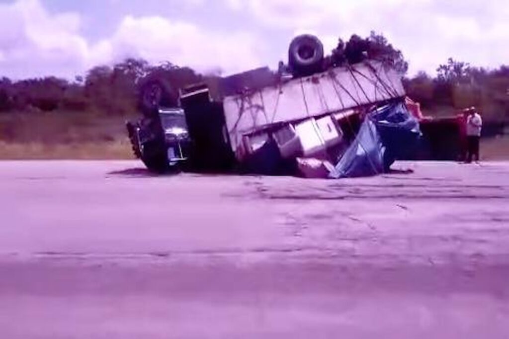 Camión volcado en carretera con carga suelta.