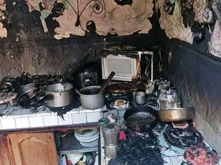 Cocina dañada por incendio, ollas y microondas quemados.