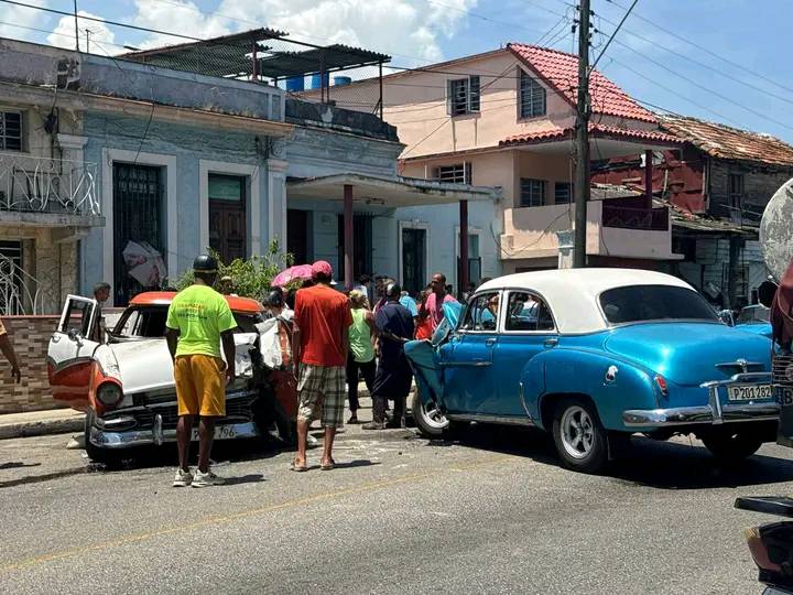 Accidente de coches antiguos en calle concurrida.