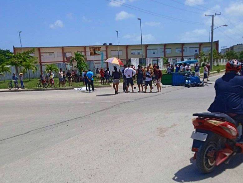 Personas reunidas en calle con edificio al fondo.