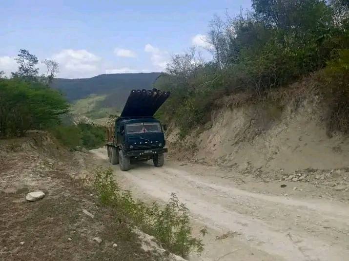 Camión militar en camino rural montañoso.