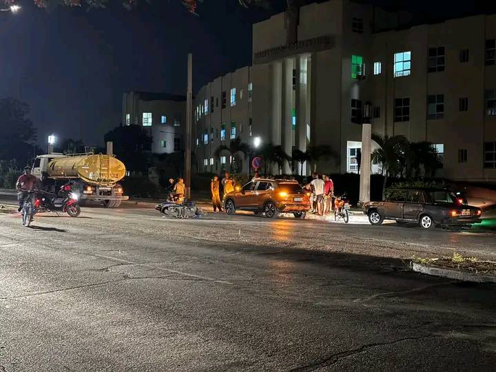 Accidente de tráfico nocturno en calle iluminada.
