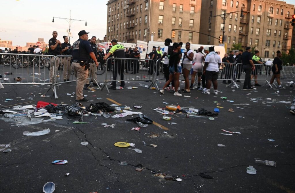 Calle con basura y personas detrás de barreras