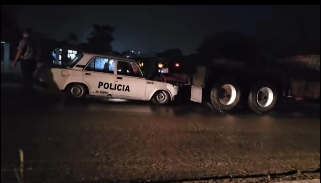 Coche de policía accidentado con camión por la noche.