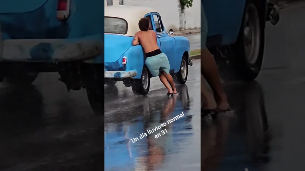 Persona empuja un coche bajo la lluvia