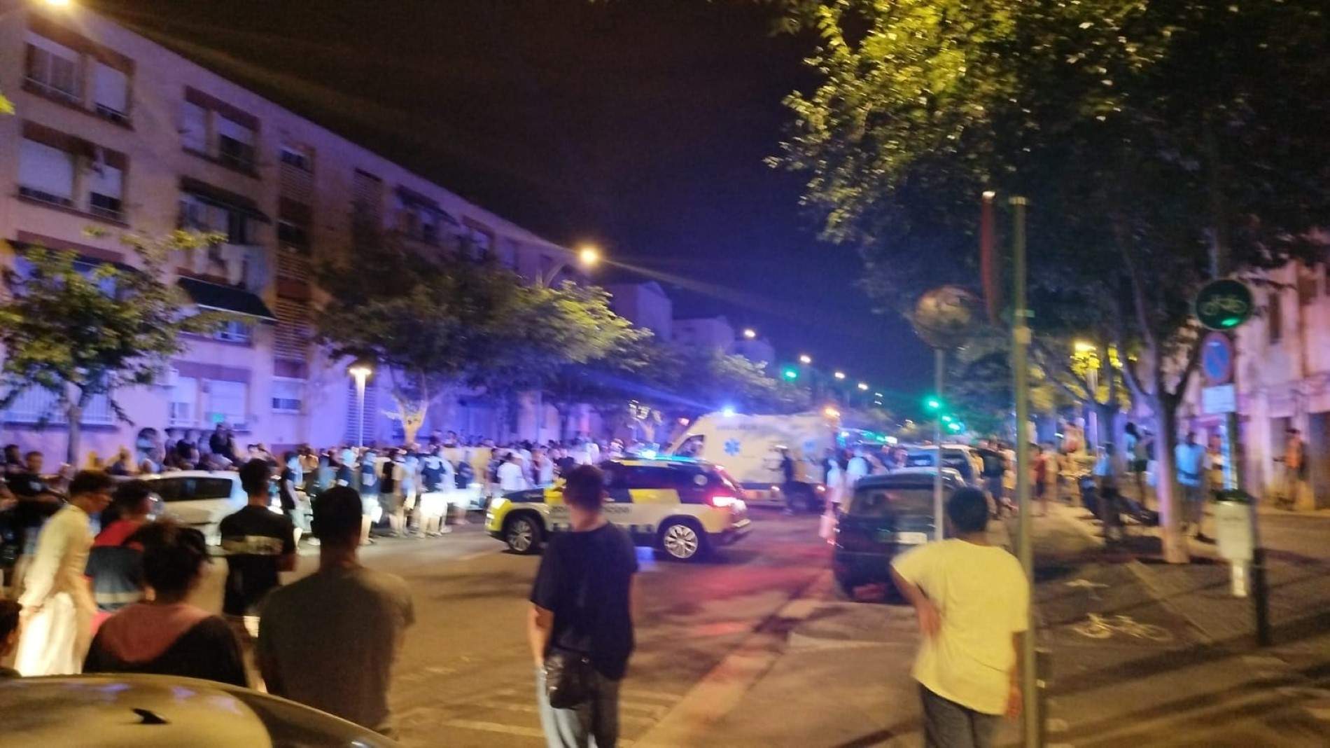 Multitud observa escena con policía y ambulancia