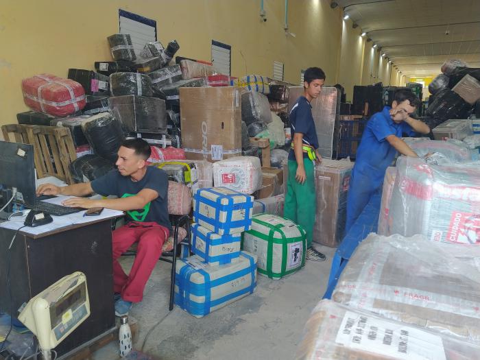 Hombres trabajando en almacén con paquetes y cajas.