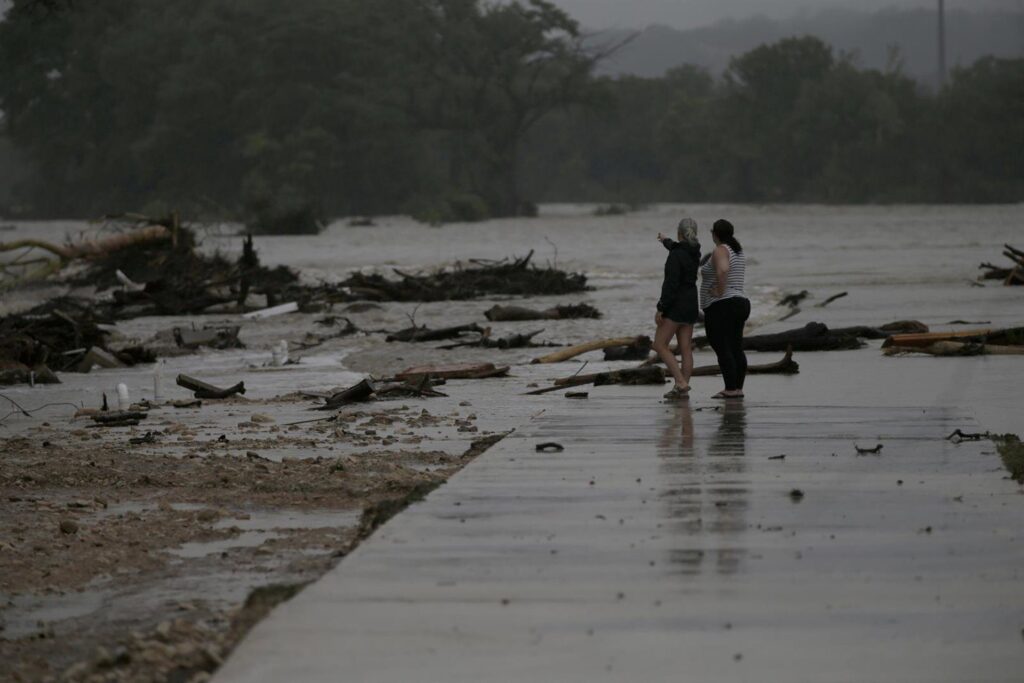 Dos personas observan inundación en un río desbordado.