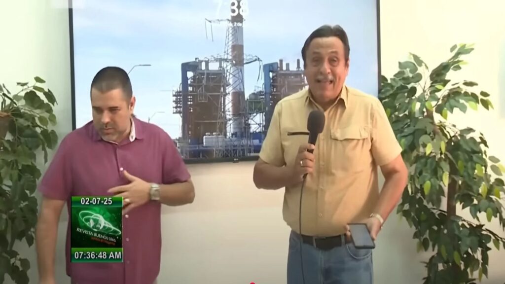 Hombres hablando frente a imagen de planta industrial.