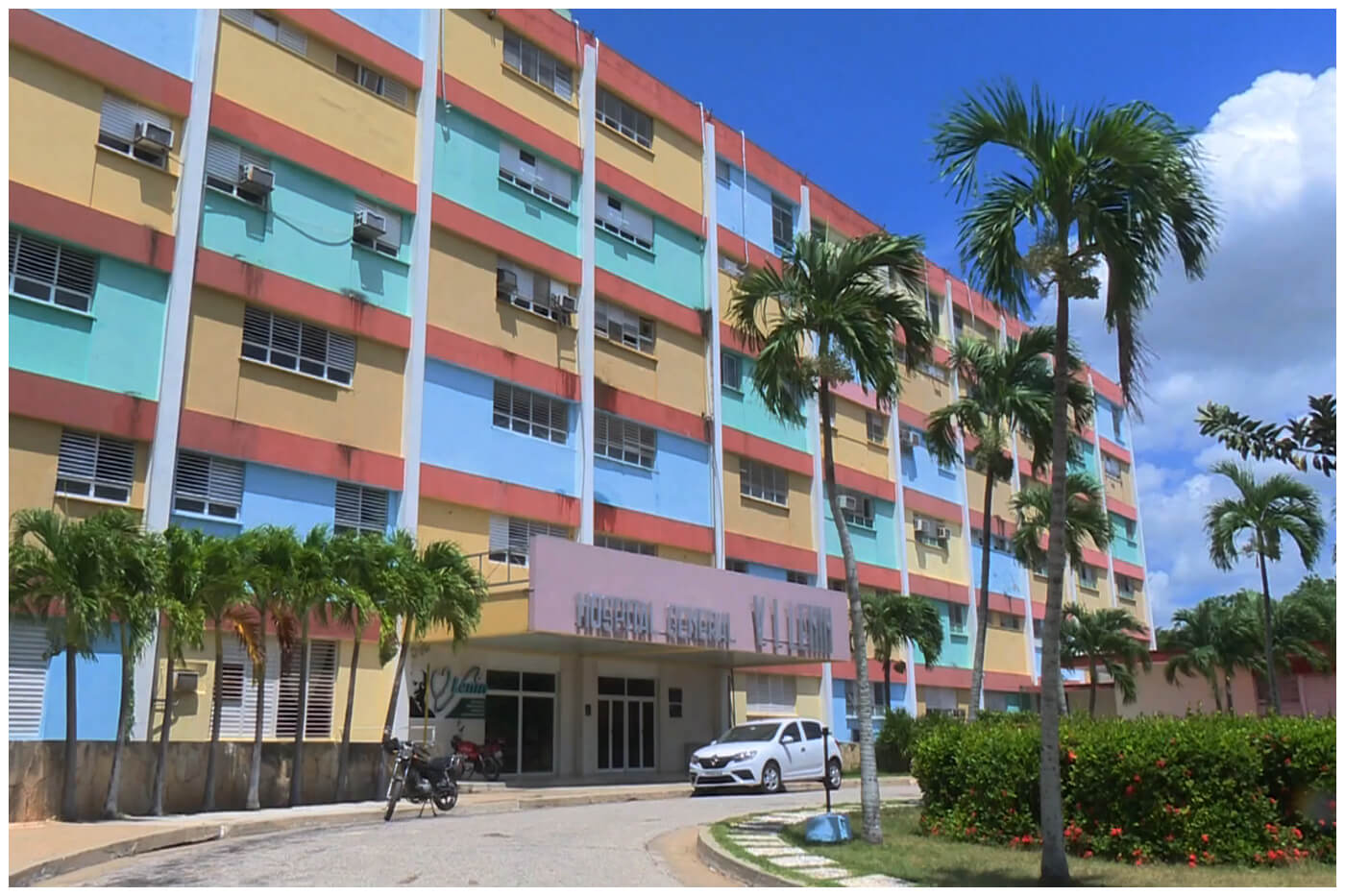 Hospital general colorido rodeado de palmeras.