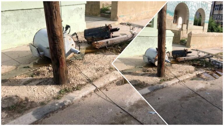 Transformador caído junto a poste de madera.